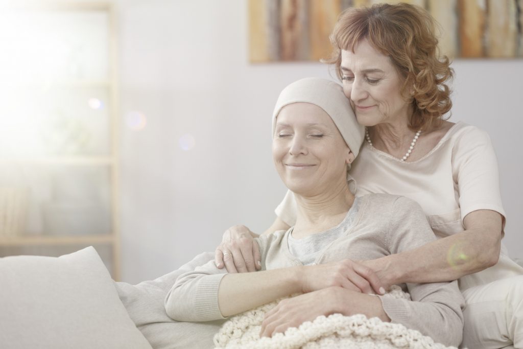 Happy sick woman after chemotherapy and elderly mother hugging her